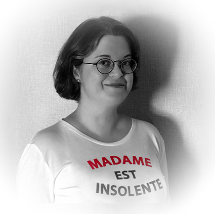 A photograph of Bethan Tovey-Walsh, a middle-aged white woman wearing
        glasses and smiling at the camera. She is wearing a T-shirt with the French words 'Madame
        est insolente' on it.